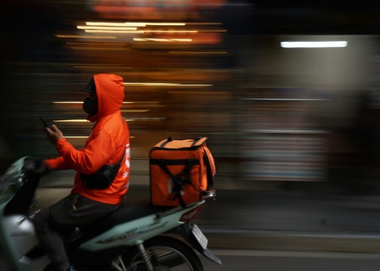 A person in an orange jacket riding a motorcycle