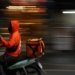 A person in an orange jacket riding a motorcycle