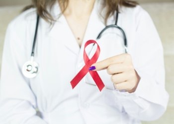 a woman in a white shirt holding a red ribbon