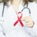 a woman in a white shirt holding a red ribbon