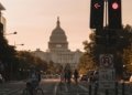people biking on road and different vehicles viewing United States Capitol during daytime screenshot