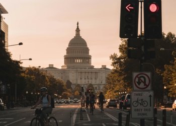 people biking on road and different vehicles viewing United States Capitol during daytime screenshot