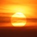 A breathtaking sunset with the sun setting behind clouds and birds flying across the vibrant sky.