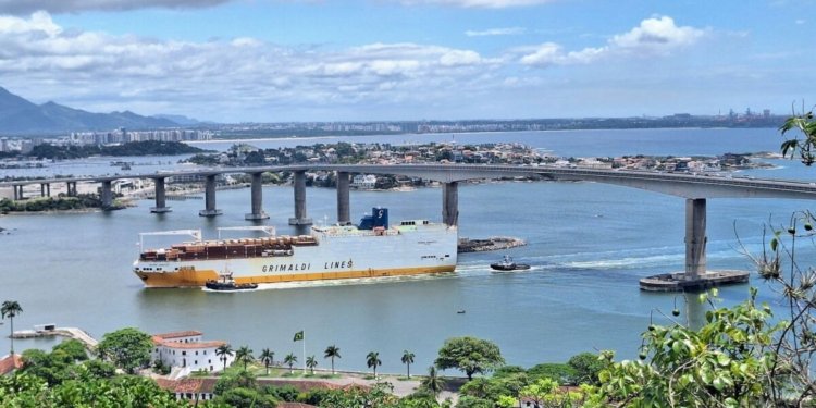 a large boat traveling down a river next to a bridge