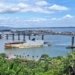 a large boat traveling down a river next to a bridge