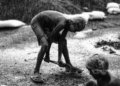 Black and white photo of children working under the rain in rural Bangladesh.