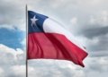Chilean flag waving against a cloudy sky, symbolizing national pride and unity.