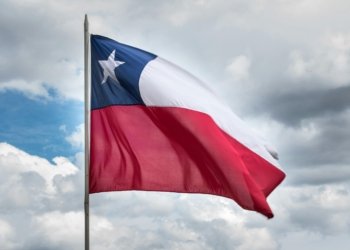 Chilean flag waving against a cloudy sky, symbolizing national pride and unity.