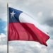 Chilean flag waving against a cloudy sky, symbolizing national pride and unity.