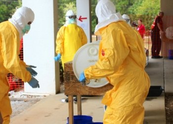 Professionals in yellow PPE suits attending to a procedure outdoors for safety training.