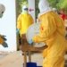 Professionals in yellow PPE suits attending to a procedure outdoors for safety training.