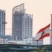 Urban skyline of Beirut with a prominent Lebanese flag gently waving at sunset.