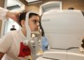 Young boy receiving an eye exam using autorefractor at a clinic. Healthcare concept.