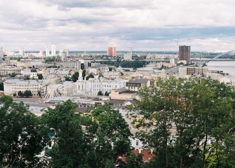 A scenic aerial view of Kyiv cityscape featuring a Ferris wheel and iconic landmarks.