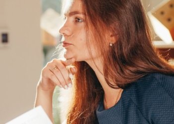 a woman holding paper while thinking