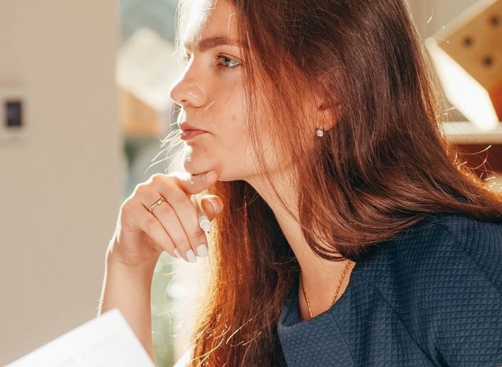 a woman holding paper while thinking