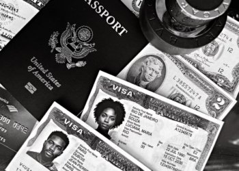 A black and white composition of a US passport, visas, and currency, showcasing travel essentials.