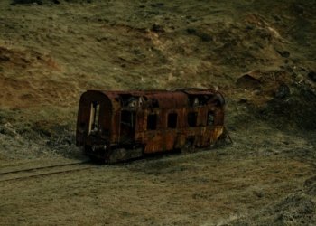 A decaying train car sits isolated in a São Paulo grassland, symbolizing neglect and history.