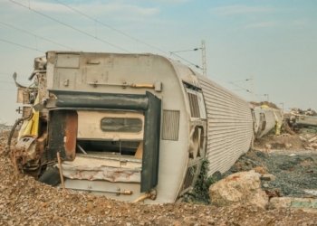 A derailed train lies overturned on a barren track, showcasing a scene of destruction.