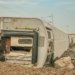 A derailed train lies overturned on a barren track, showcasing a scene of destruction.