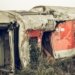 A dilapidated train carriage lying abandoned in an overgrown field after derailing.