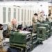 A group of military personnel in uniforms using computers and communication equipment in a secure indoor facility.