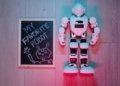 Playful scene of a white robot toy and chalkboard drawing on wooden floor.