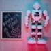 Playful scene of a white robot toy and chalkboard drawing on wooden floor.